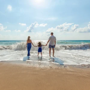Family holding hands on a sunny beach.